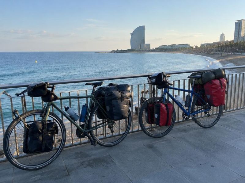 Two loaded touring bikes by the sea in Barcelona